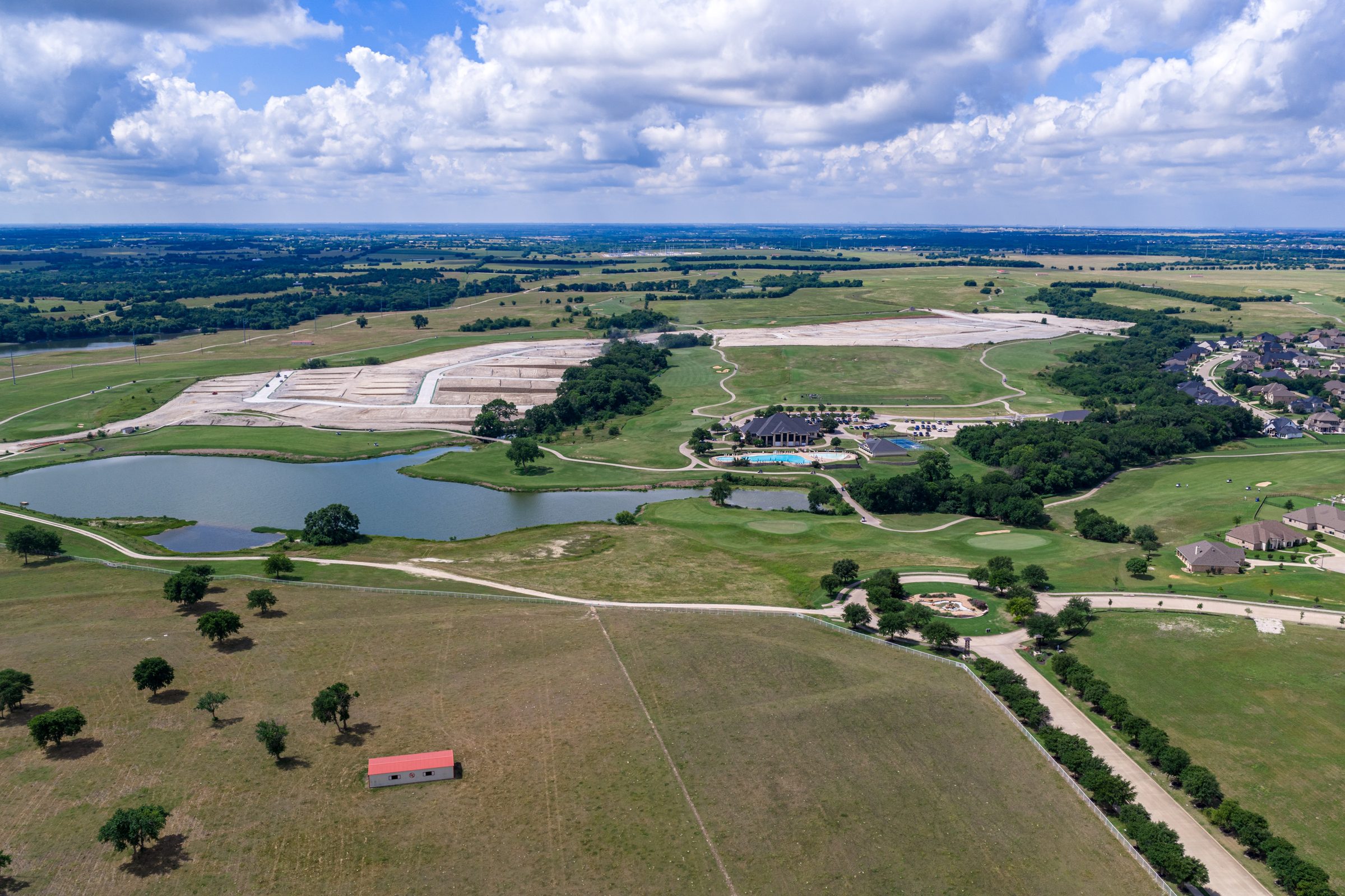 Aerial view over The Bridges showing the lake, amenity center and a new phase of homesites being developed