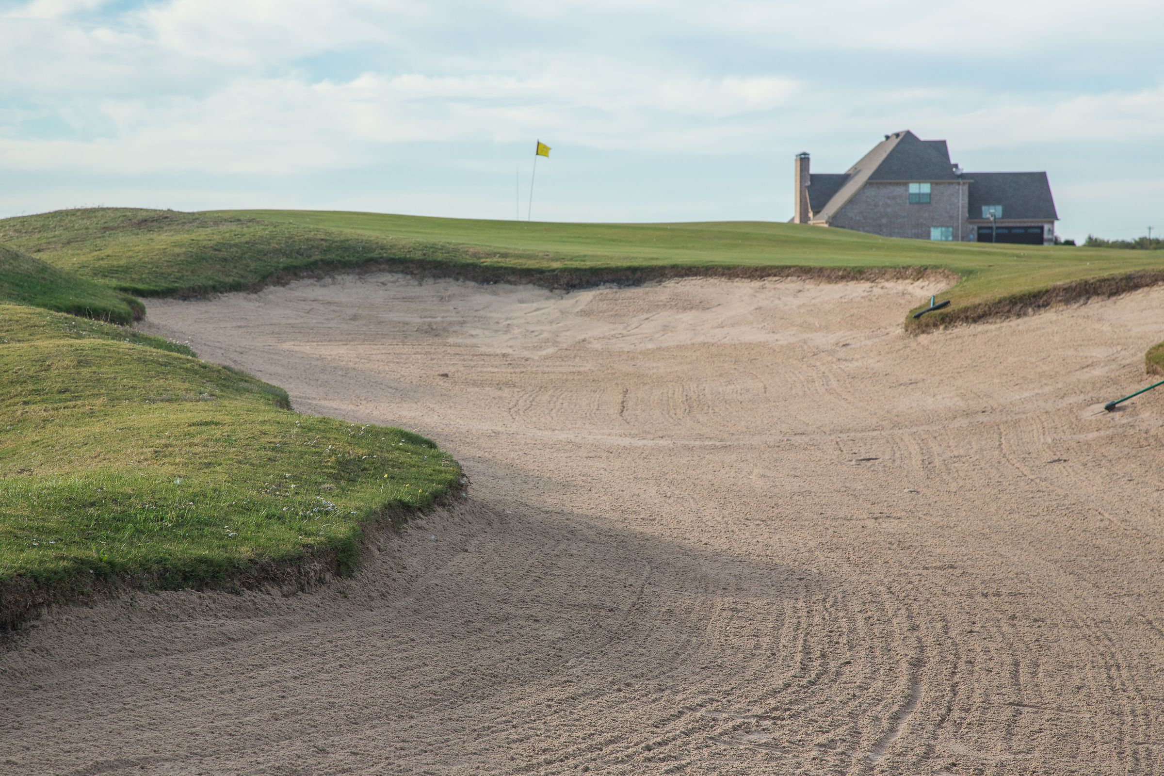 Sand bunker and green with a custom home overlooking the course at The Bridges