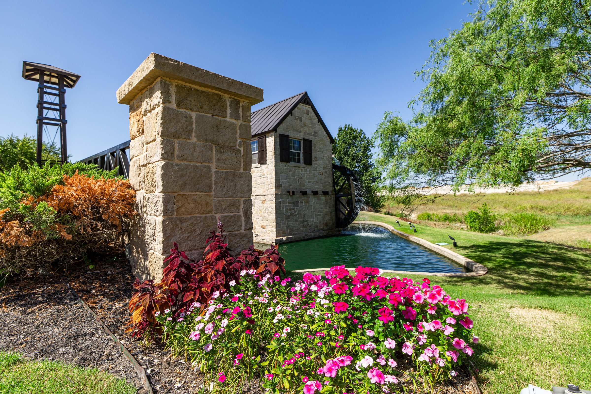 Stone pillar, water feature and flowers at the entrance to The Bridges