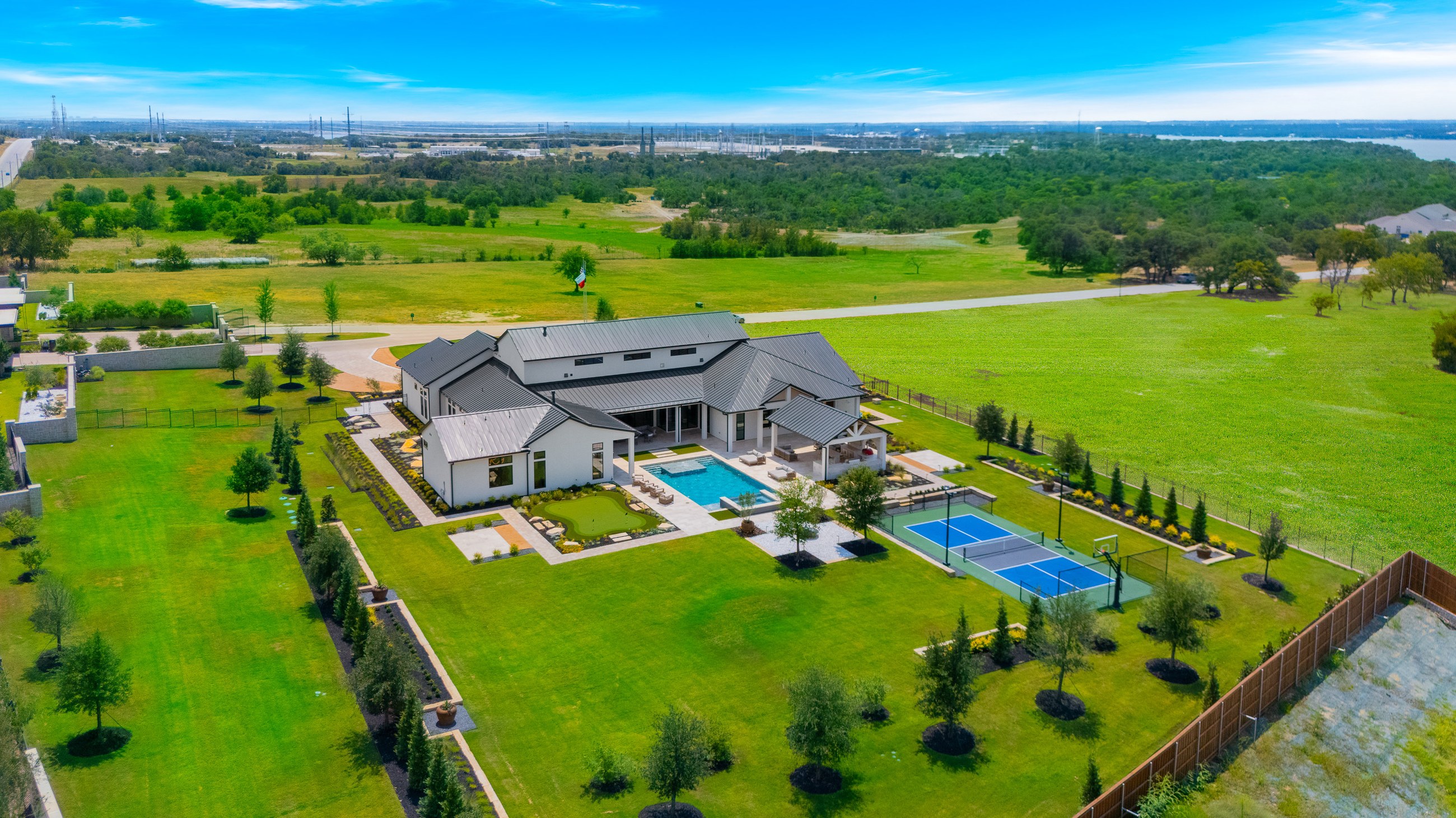 Aerial view of a custom home estate with a pool and manicured grounds