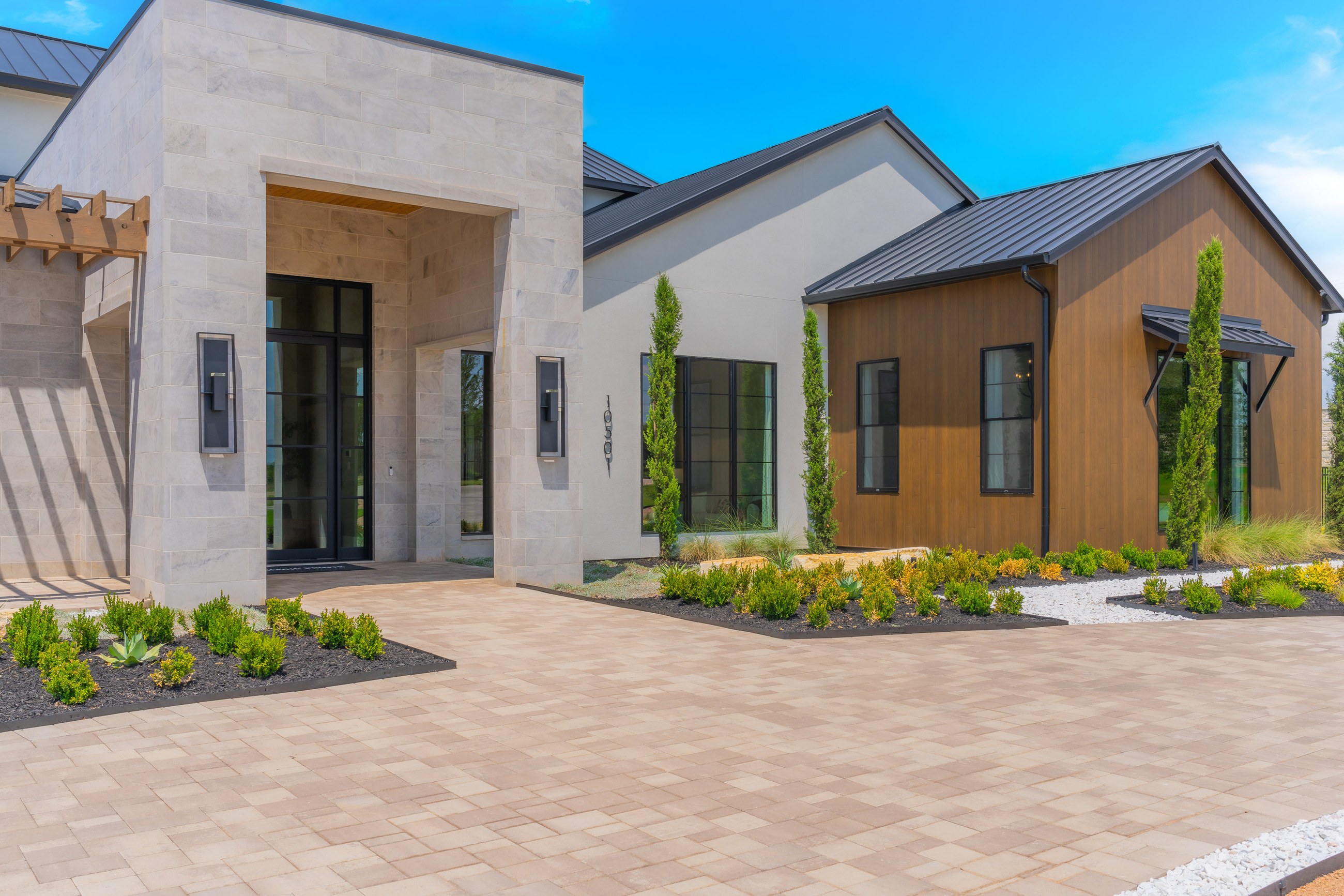 Custom home entry courtyard with stone paving and architectural stucco and wood detailing
