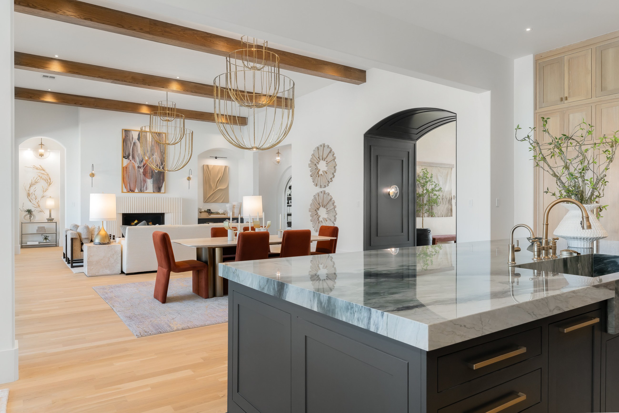 Custom kitchen with dark cabinetry, a waterfall island and brass fixtures