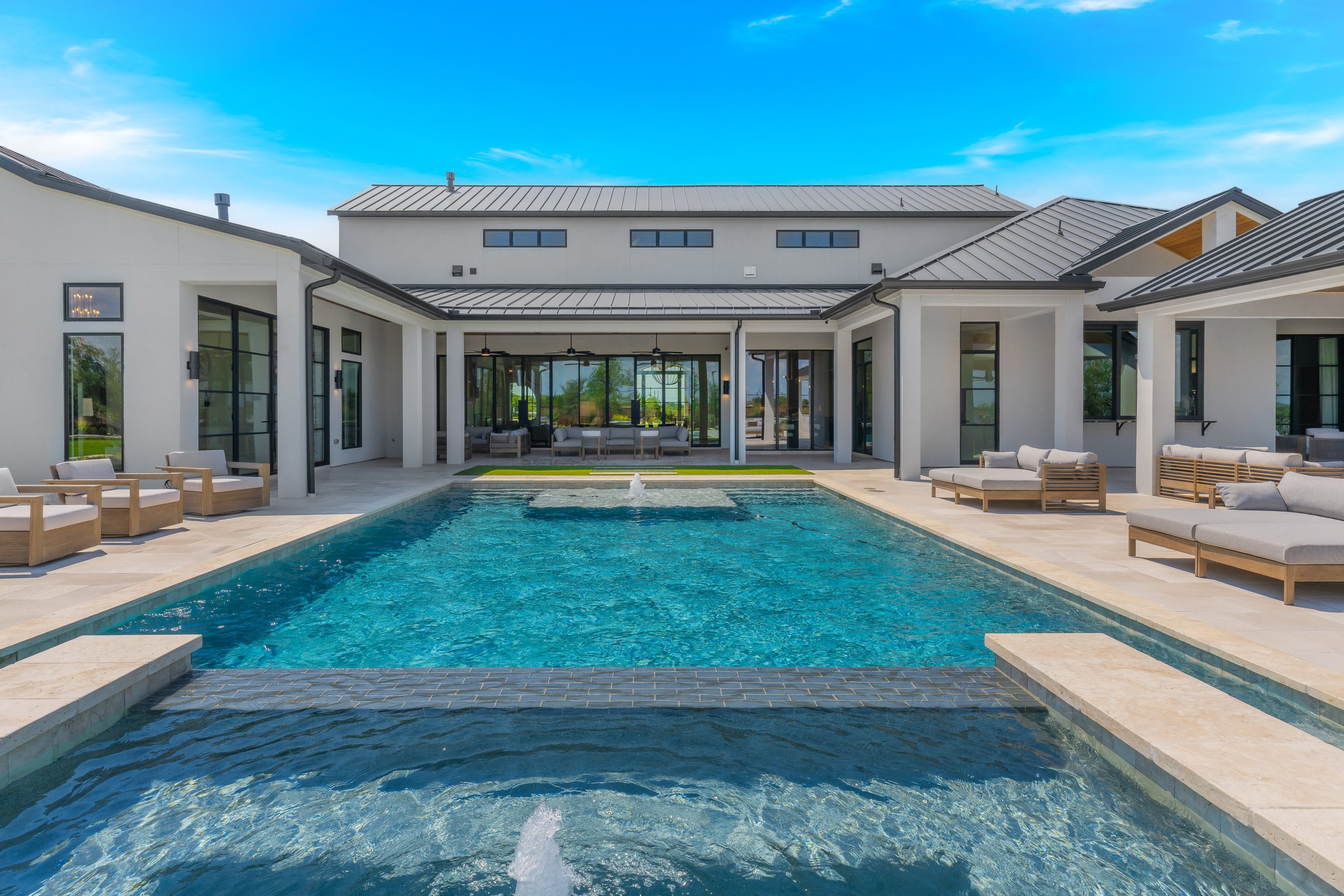 Covered outdoor living area with a pool, spa and artificial-turf putting green