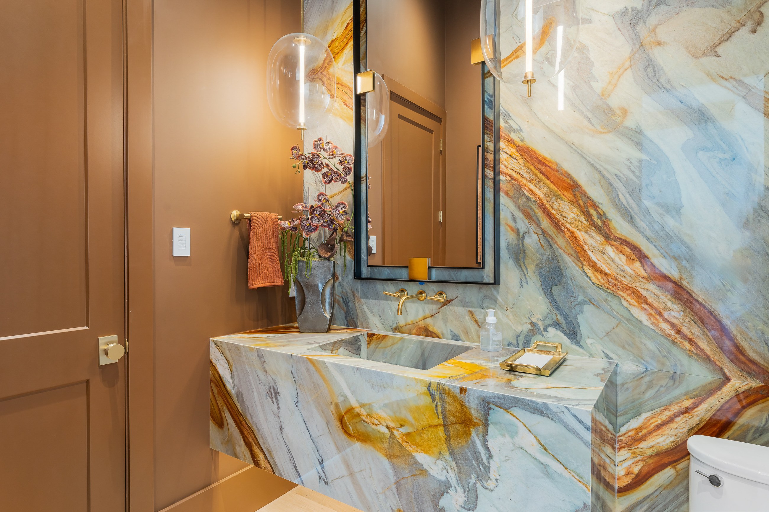 Primary bath with a book-matched stone wall, soaking tub and dual vanities